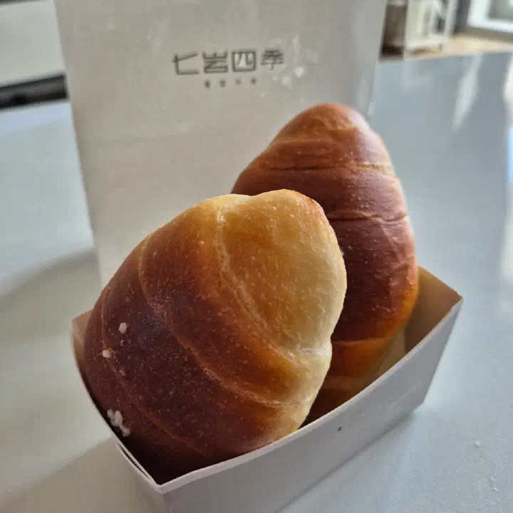 칠암사계 소금빵 두 개, 흰 종이 트레이와 로고 쇼핑백