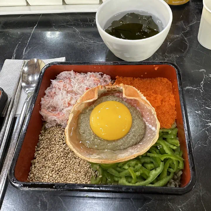 게딱지에 성게알과 노른자를 올리고 게살, 날치알, 오이 등을 곁돌려 담은 비빔밥 클로즈업 사진