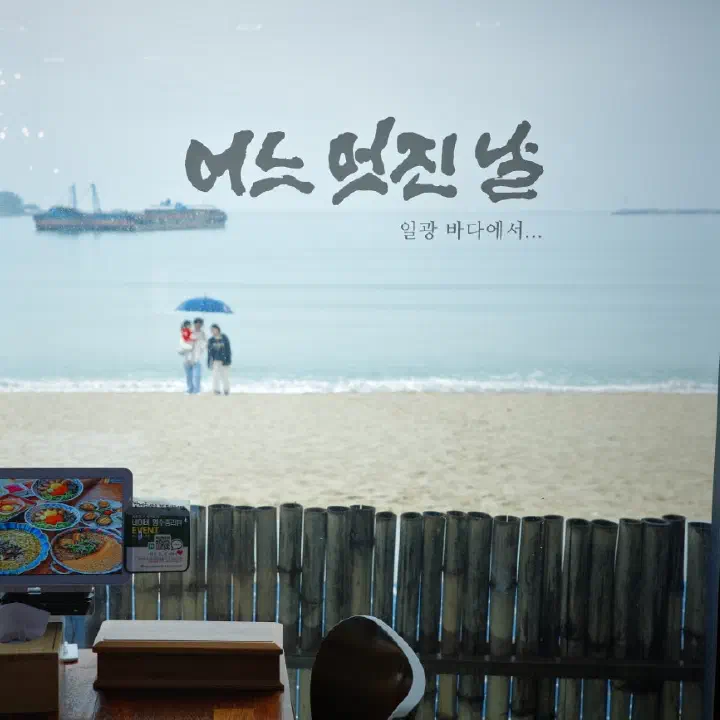 어느멋진날 매장 창문에 일광 바다라는 글귀와 함께 모래사장과 바다 풍경이 비치는 모습