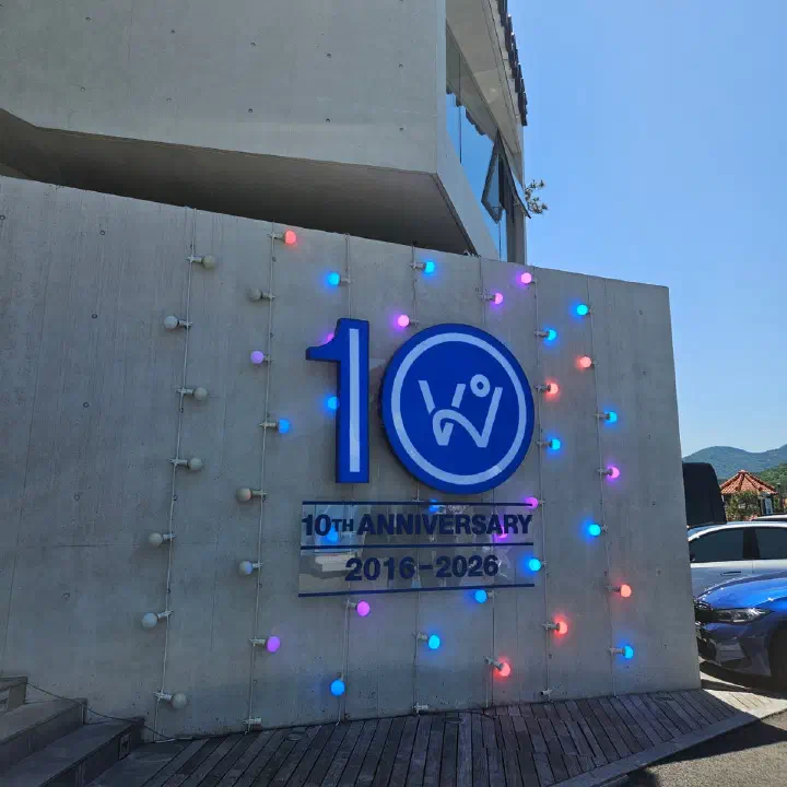 웨이브온 커피 콘크리트 외벽의 10주년 기념 사인과 색색 전구