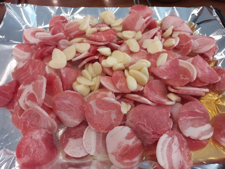 청주 봉용불고기 대패삼겹살 위에 통마늘을 올려 함께 굽는 모습