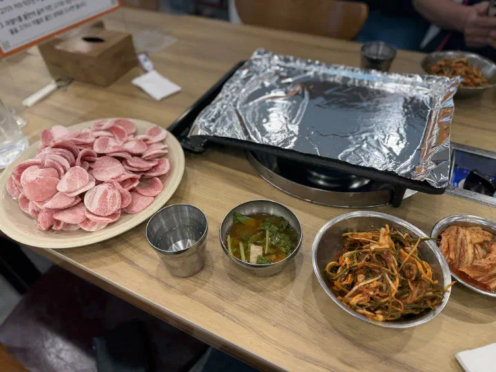 청주 봉용불고기 자리에 세팅된 빈 불판과 돼지고기 반찬 기본 상차림