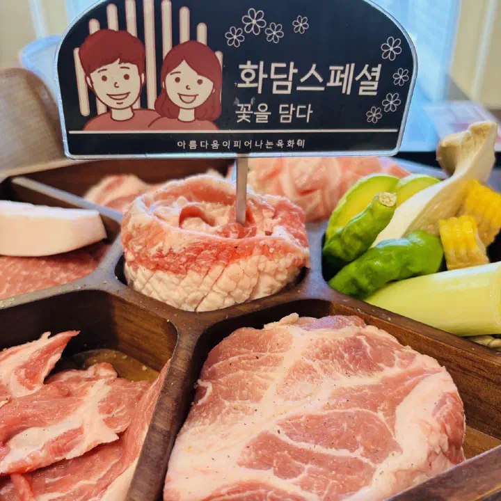 육화미 천안본점의 화담 스페셜 돼지고기 모둠이 나무 트레이에 담겨 있고, 앞쪽 칸에 두툼한 생삼겹살과 목살이 보이는 사진