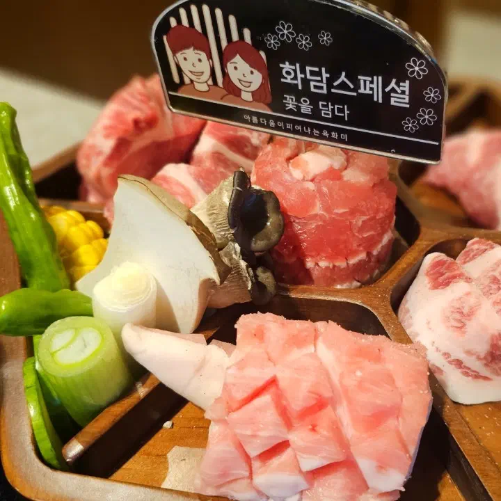 육화미 천안본점의 화담 스페셜 생고기 모둠이 꽈리고추, 대파, 새송이버섯과 함께 나무 쟁반에 담겨 나온 모습