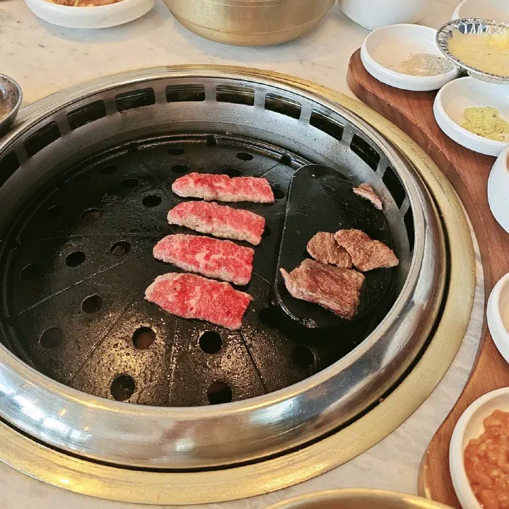 육화미 천안본점 원형 불판에서 마블링 있는 소고기를 굽고 있는 모습