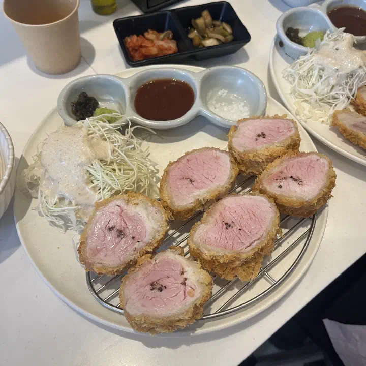 심지에서 돈가스를 반으로 잘라 분홍빛 속살 단면이 보이도록 접시에 담아낸 모습
