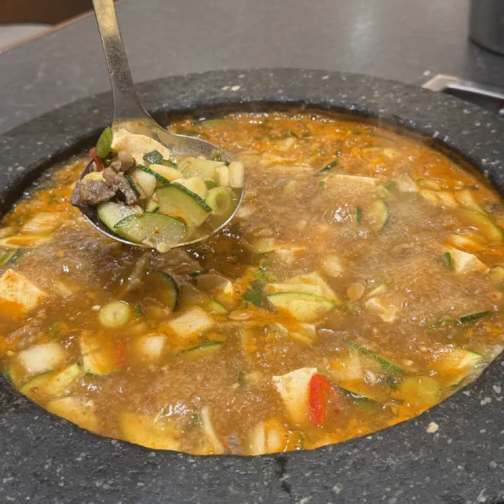 연화37 된장찌개, 끓는 돌솥에서 국자로 떠 올린 애호박과 두부