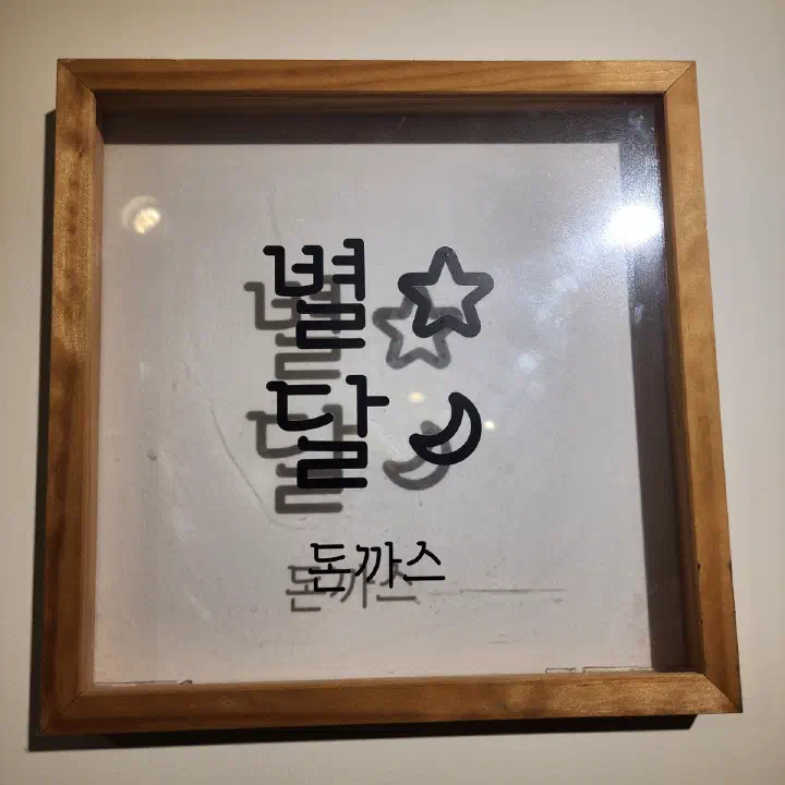 별달돈까스 벽에 걸린 원목 액자 로고, 별과 달 그림이 들어간 글자