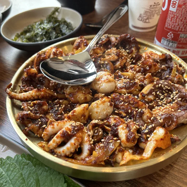 손의손 본점에서 매콤한 빨간 양념에 볶은 낙지 요리를 깨를 뿌려 놋그릇에 담아 낸 모습