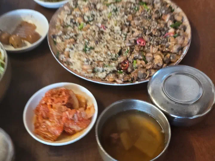 반반으로 담긴 향화정 꼬막무침비빔밥과 김치, 소고기무국 밑반찬