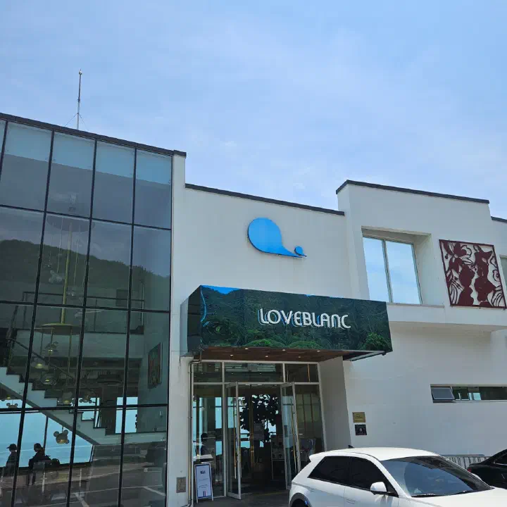 러블랑 정면 출입구와 푸른 고래 로고, 입구 옆에 주차된 승용차