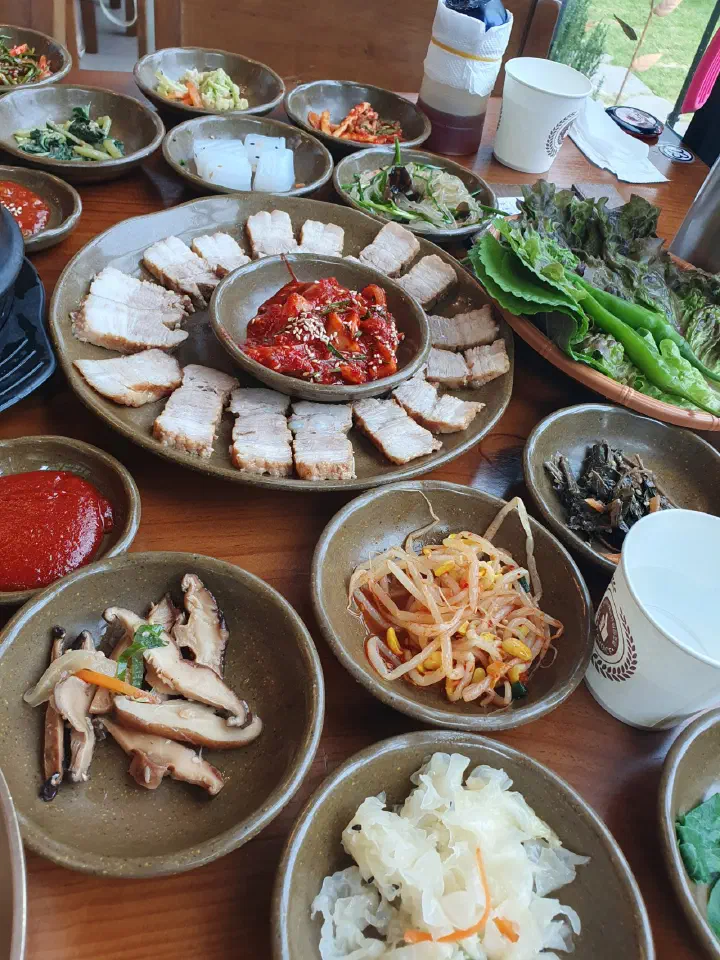 김삿갓밥집 수육과 상추 깻잎 쌈채소, 나물 반찬이 함께 놓인 넓은 테이블