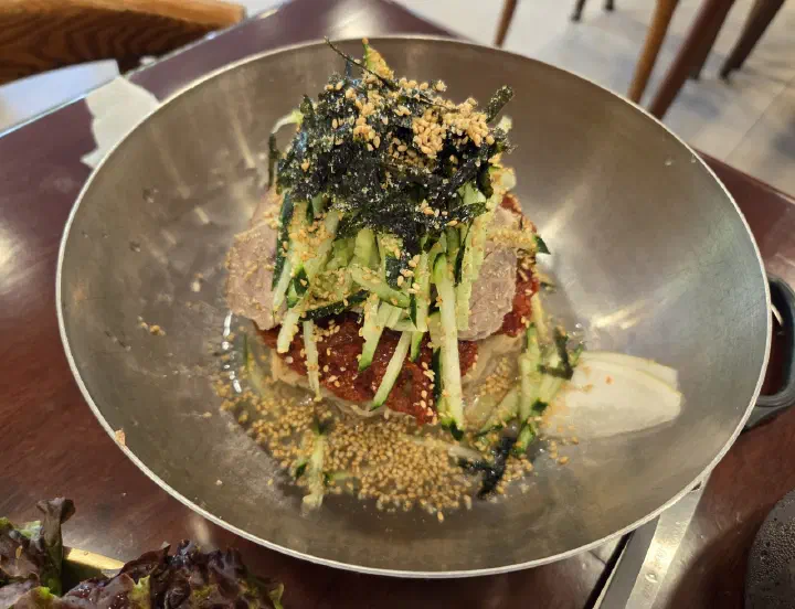 윤밀원 비빔막국수 위에 오이채와 김가루, 통깨를 올린 한 그릇