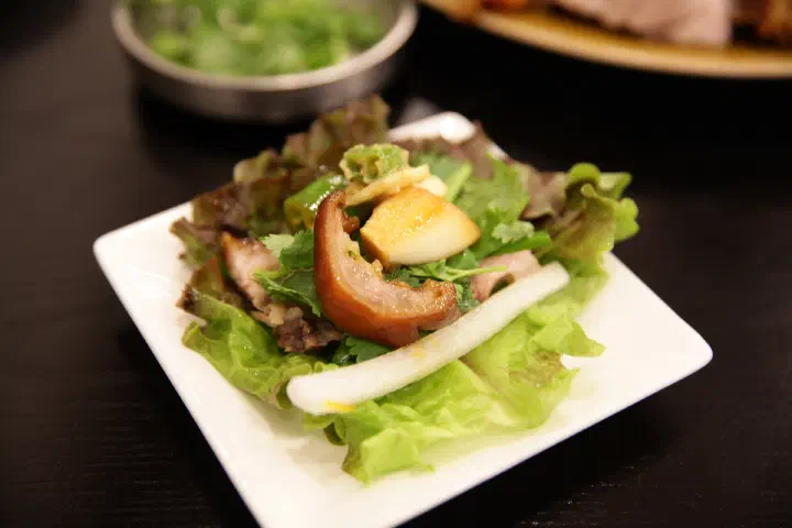 윤밀원 족발에 고수와 무절임을 얹어 상추에 싸 먹는 족발 쌈 한 점