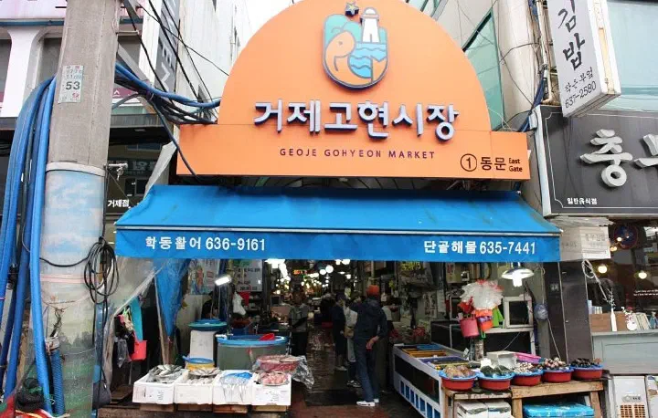 거제 고현시장 동문 입구의 주황색 아치 간판과 시장 안 상점가