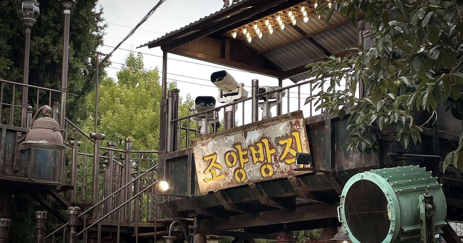 조양방직 야외 마당, 녹슨 철판 간판이 걸린 철제 데크와 전구 조명