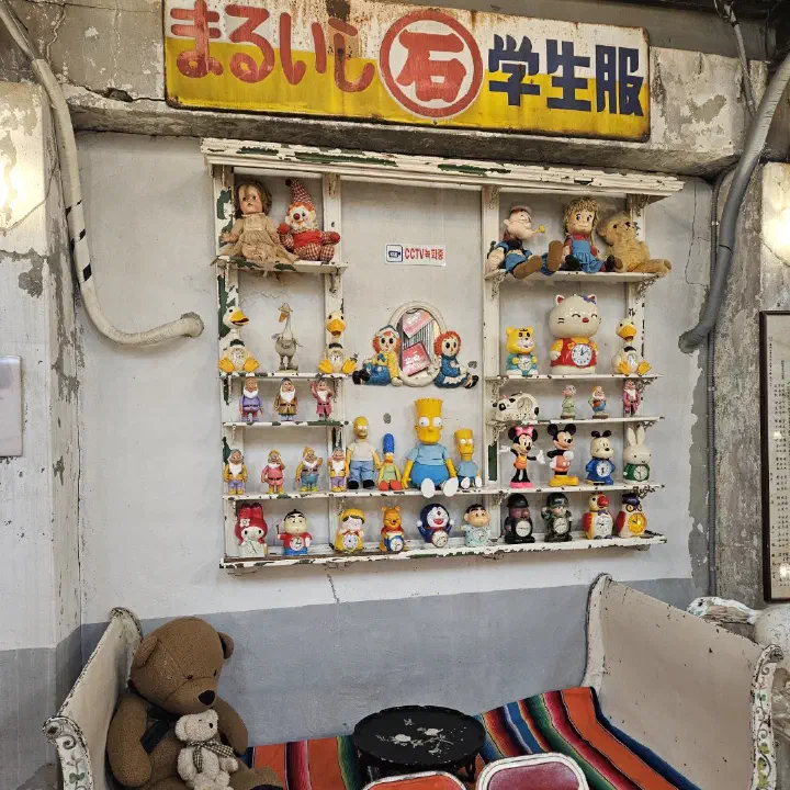 조양방직 시멘트 벽 선반, 줄지어 놓인 빈티지 캐릭터 인형과 시계