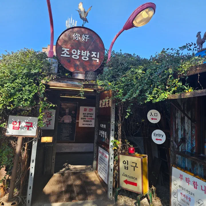 조양방직 입구, 덩굴 위로 솟은 녹슨 둥근 간판과 입구 안내판