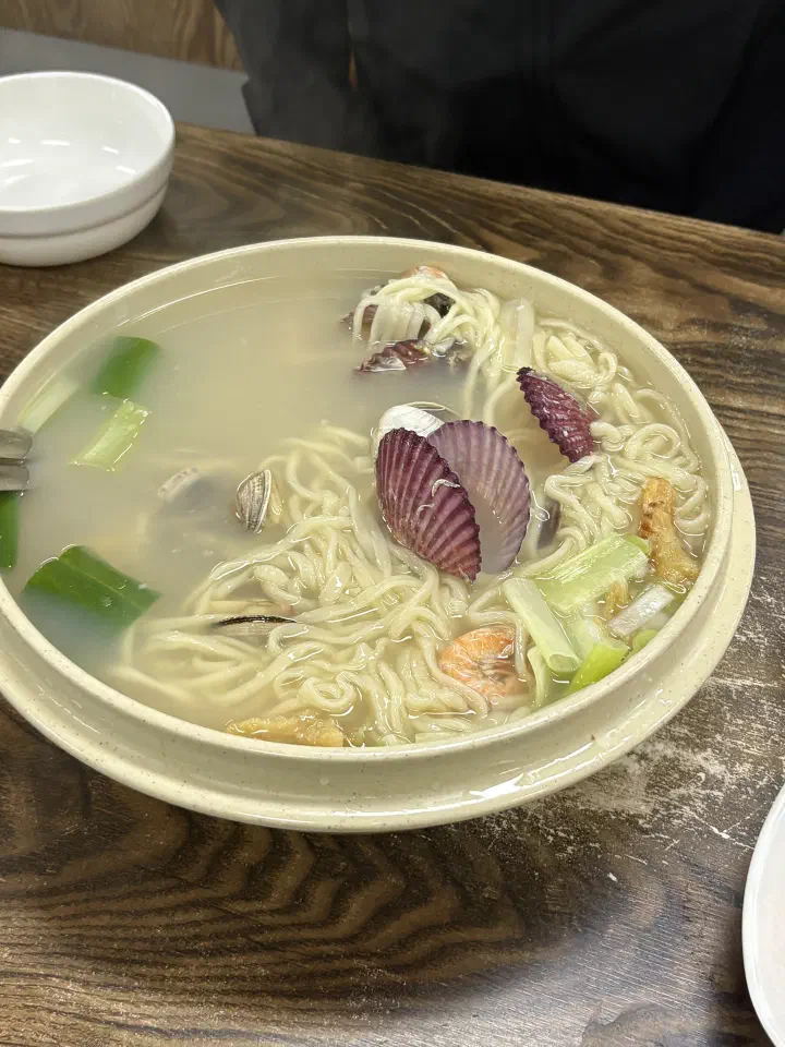 영종도 황해해물칼국수 본점의 해물칼국수 한 대접이 나무 테이블 위에 놓인 모습