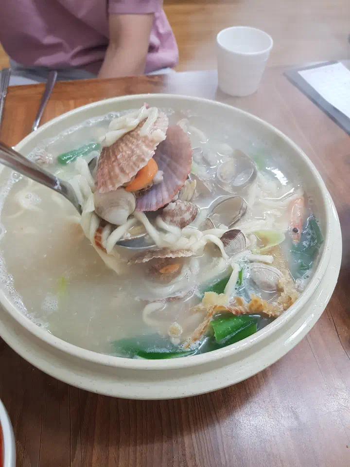 황해해물칼국수 해물칼국수를 국자로 떠올리자 칼국수 면과 조개가 함께 담긴 모습