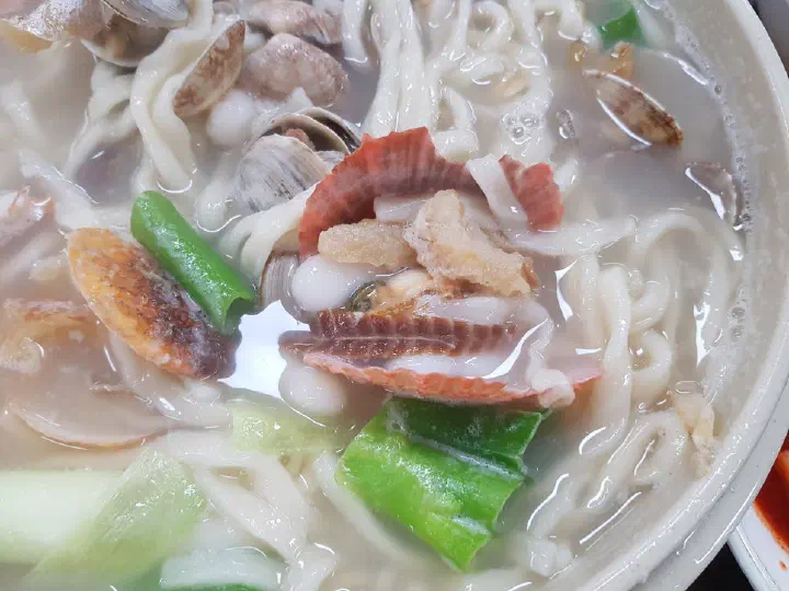 조개와 쫄깃한 조랭이떡, 도톰한 칼국수 면이 어우러진 해물칼국수 클로즈업
