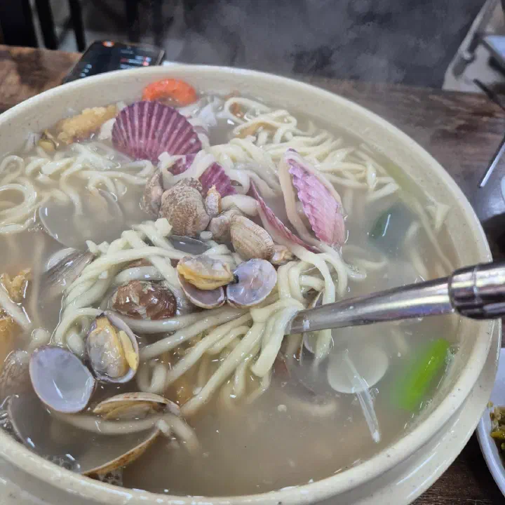 김이 오르는 황해해물칼국수에 바지락과 동죽, 백합 등 조개가 가득 담긴 클로즈업