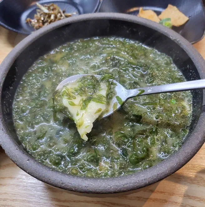 몸국 안에 들어 있는 쫄깃한 수제비를 숟가락으로 건져 올린 모습