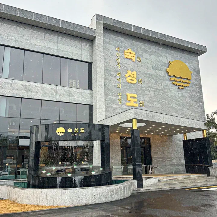 회색 석재 외벽에 금색 간판이 달린 숙성도 중문점 건물 외관과 입구 앞 분수대