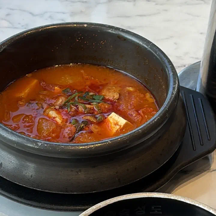 숙성도 중문점 검은 뚝배기에 담긴 붉은 국물의 두부 김치찌개 접사 사진