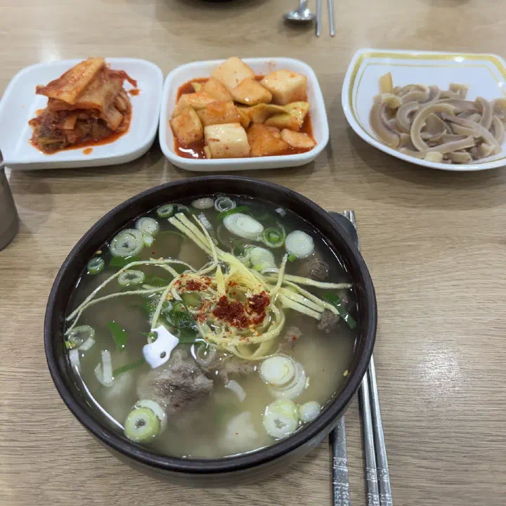 나주곰탕 하얀집에서 맑은 곰탕 한 그릇과 김치, 깍두기, 수육 반찬이 놓인 식탁을 위에서 찍은 사진