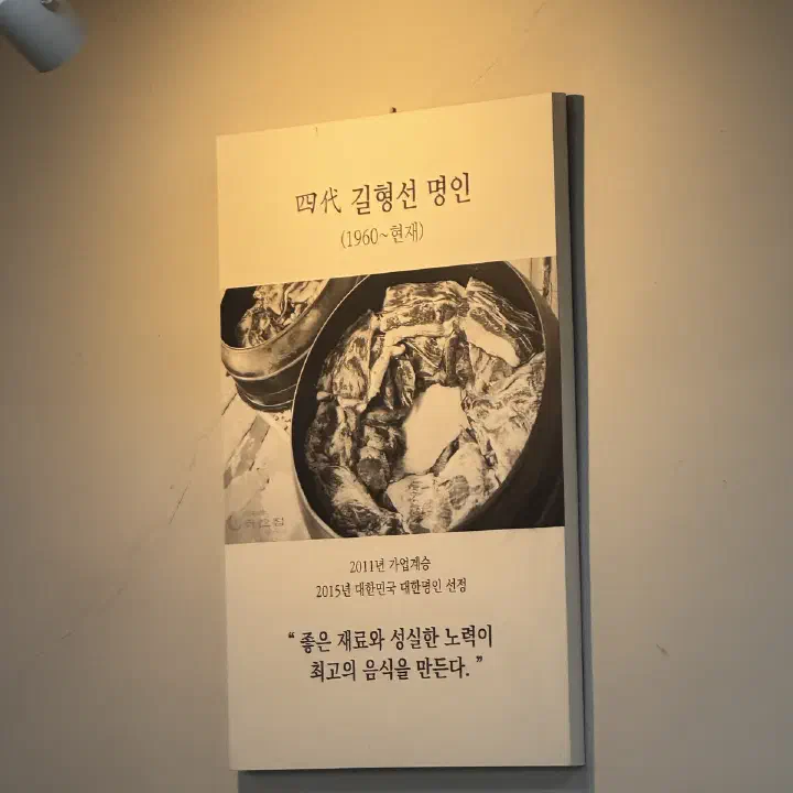 나주곰탕 하얀집 벽에 걸린 4대 길형선 명인 소개 액자로, 곰탕 뚝배기를 흑백으로 담은 사진이 함께 있다