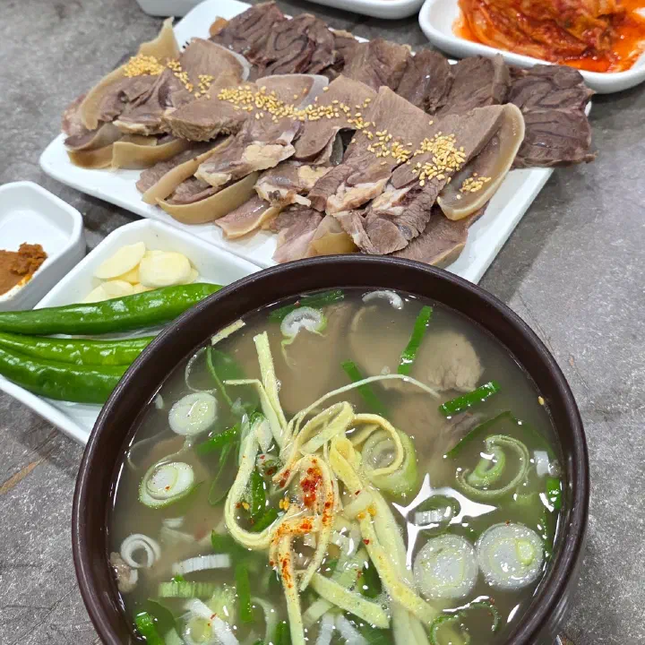 나주곰탕 하얀집의 얇은 대파 채를 올린 맑은 곰탕 한 그릇과, 뒤에 놓인 편육 접시와 김치 접시를 위에서 찍은 사진