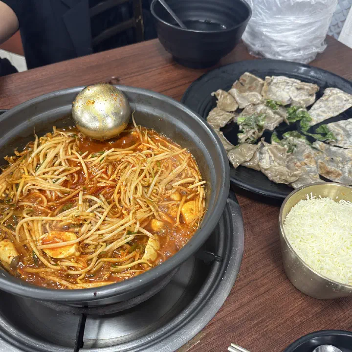 감동식당 노원본점에서 콩나물과 곱창이 듬뿍 든 얼큰한 전골에 치즈 사리를 곁들여 먹는 모습
