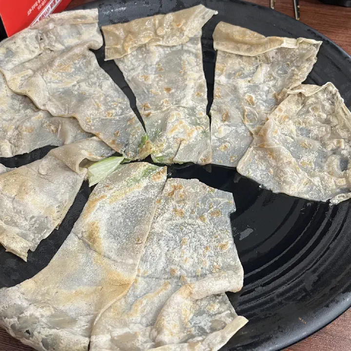 감동식당 노원본점에서 파전 또는 부침개를 부채꼴로 잘라 검은 접시에 담은 모습