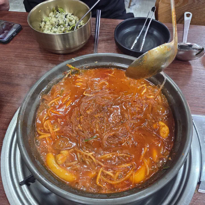 감동식당 노원본점에서 당면과 떡이 들어간 빨간 국물 요리를 큰 들통 냄비에 끓여 국자로 담아내는 모습