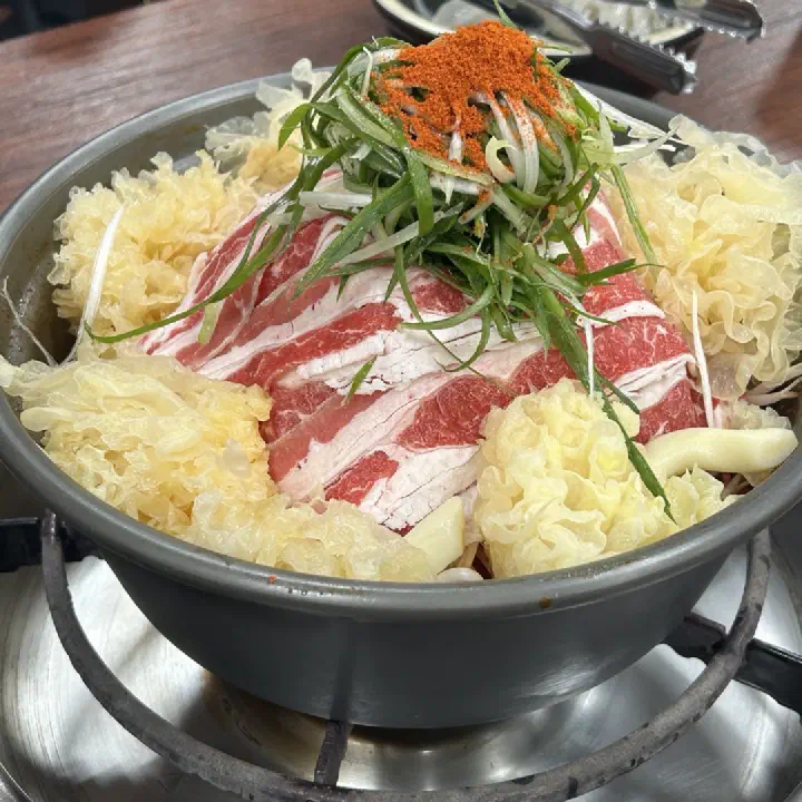 감동식당 노원본점에서 얇게 썬 삼겹살과 대파, 양배추를 넉넉히 담은 전골 냄비를 클로즈업한 사진