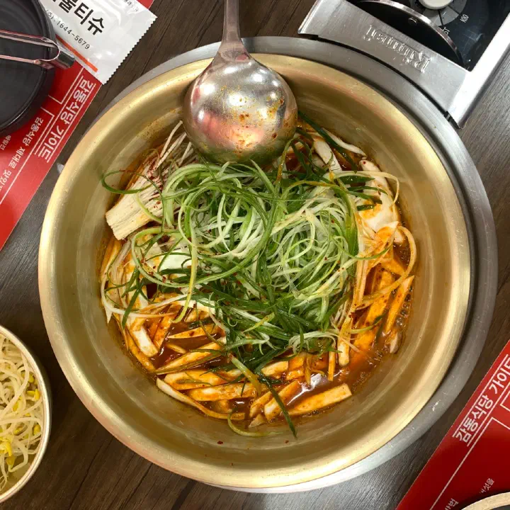감동식당에서 황동색 냄비에 담긴 매콤한 양념 찜 요리에 실파와 깻잎 채가 수북이 올라간 모습
