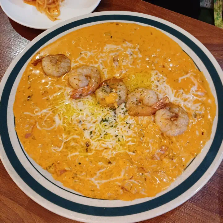 서양식당 주황빛 크림 소스 쌀 요리, 한 줄로 올린 구운 새우