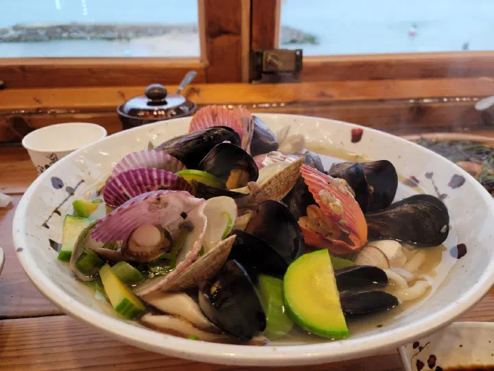 울산 나사리식당 창가 자리에서 바다를 배경으로 놓인 해물왕칼국수
